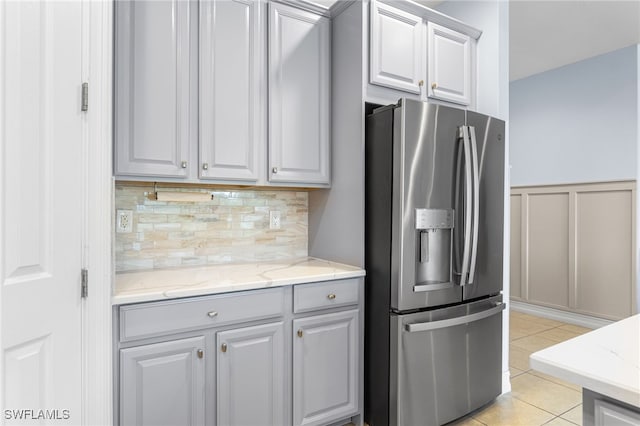 13104 Silver Thorn Loop, North Fort Myers, FL 33903 - kitchen with stainless steel refrigerator with ice dispenser, decorative backsplash, light tile patterned flooring, light stone countertops, and a decorative wall