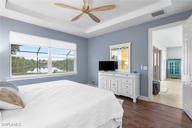 13104 Silver Thorn Loop, North Fort Myers, FL 33903 - bedroom featuring a tray ceiling, multiple windows, wood finished floors, and baseboards