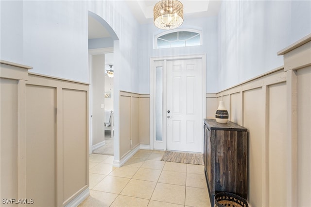 13104 Silver Thorn Loop, North Fort Myers, FL 33903 - entrance foyer with arched walkways, light tile patterned floors, a chandelier, a decorative wall, and a wainscoted wall