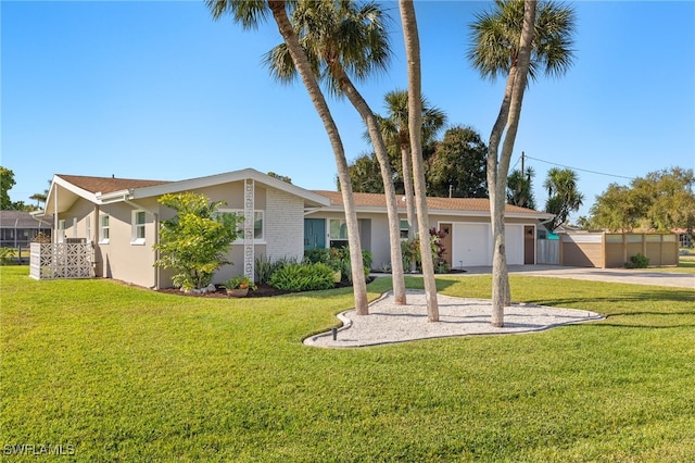 view of front of house featuring a front lawn, fence, stucco siding, a garage, and driveway