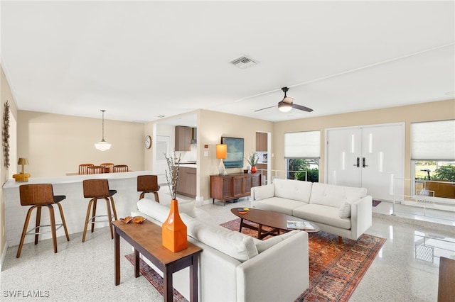 living room featuring light speckled floor, visible vents, and ceiling fan