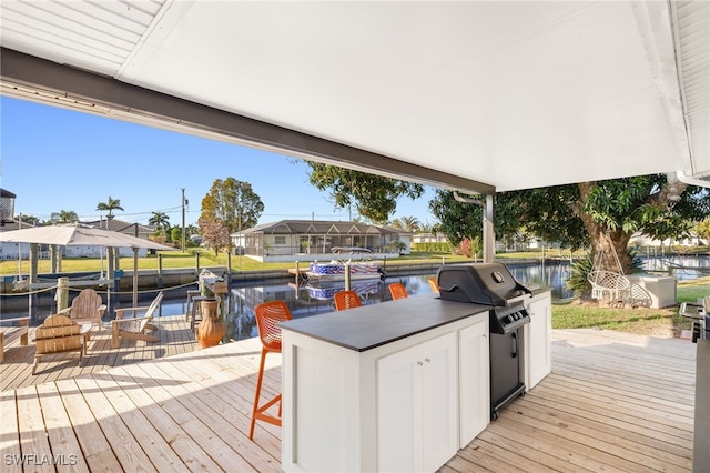 wooden terrace with grilling area, a water view, a residential view, and a boat dock