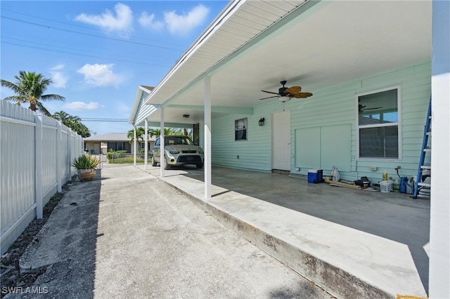 view of patio / terrace with an attached carport, concrete driveway, fence, and ceiling fan