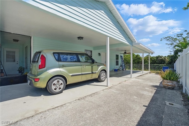 view of vehicle parking with a carport, concrete driveway, and fence