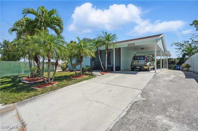 view of front of house featuring a carport, concrete driveway, a front yard, and fence