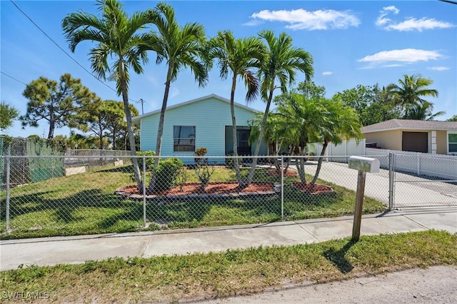 view of front of property featuring a front lawn, a garage, driveway, and a fenced front yard