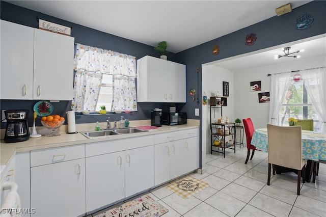 kitchen featuring white cabinetry, light countertops, and a sink