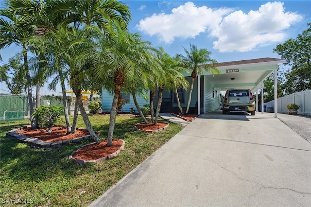 view of front facade featuring an attached carport, concrete driveway, fence, and a front lawn