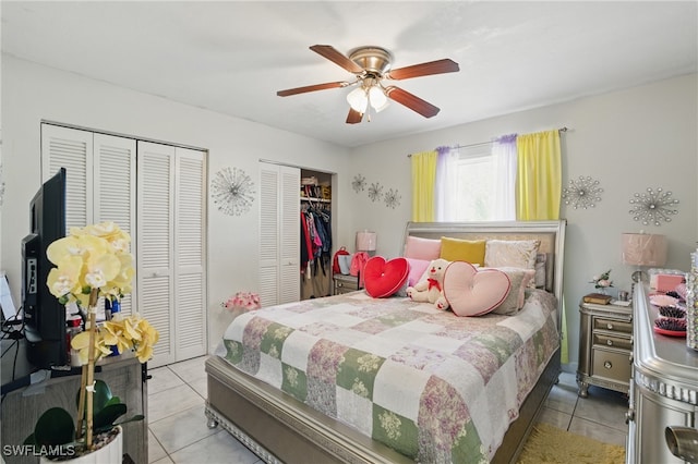 tiled bedroom with two closets and ceiling fan