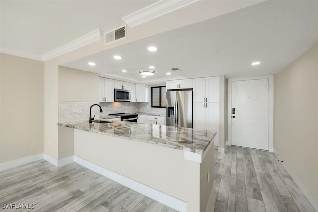 kitchen with visible vents, light stone counters, appliances with stainless steel finishes, a peninsula, and decorative backsplash