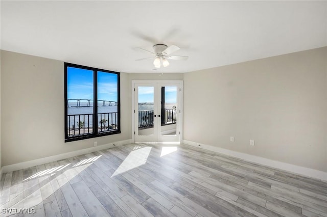 empty room with baseboards, french doors, light wood-style floors, and ceiling fan