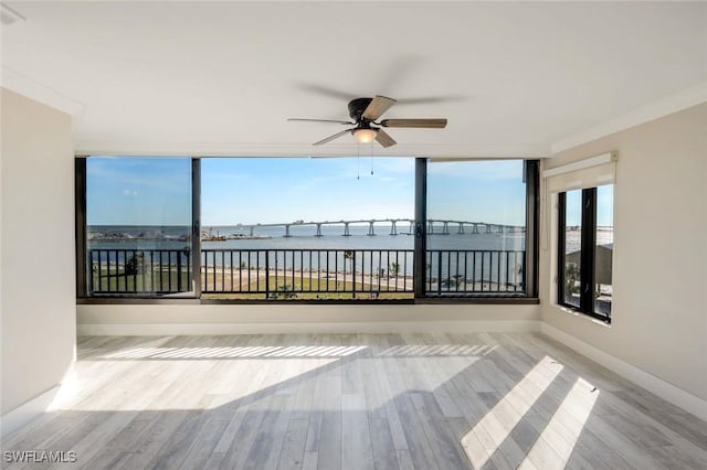 unfurnished sunroom with a ceiling fan and a water view