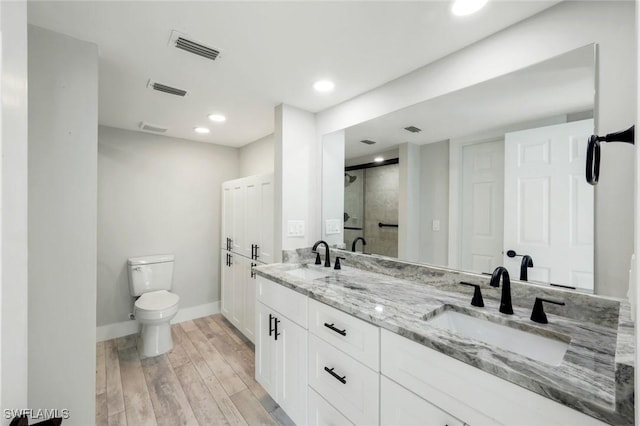 full bathroom featuring a sink, visible vents, wood finished floors, and a shower stall