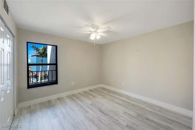 empty room featuring a ceiling fan, wood finished floors, visible vents, and baseboards