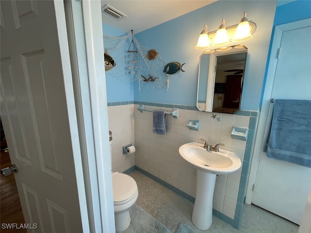 5460 Oak Ridge Ave, Fort Myers Beach, FL 33931 - bathroom featuring tile walls, a wainscoted wall, visible vents, toilet, and a sink