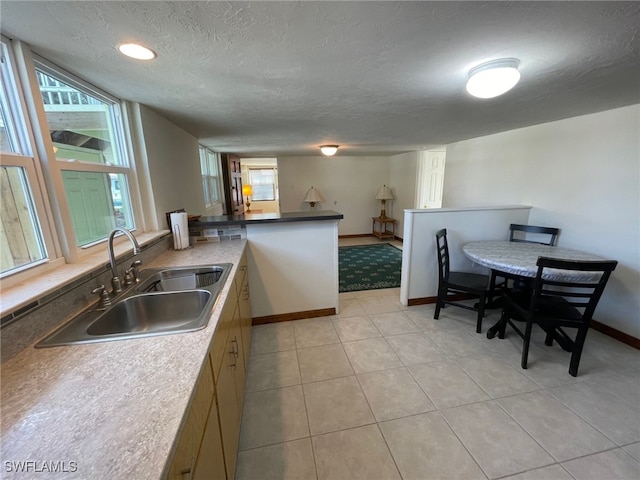 5460 Oak Ridge Ave, Fort Myers Beach, FL 33931 - kitchen with light tile patterned floors, baseboards, a textured ceiling, a sink, and a peninsula