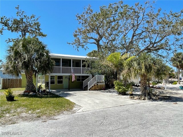 5460 Oak Ridge Ave, Fort Myers Beach, FL 33931 - view of front of house featuring stucco siding, a sunroom, fence, and concrete driveway