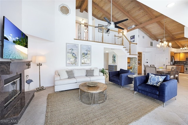 living room with stairway, lofted ceiling with beams, a tiled fireplace, wooden ceiling, and ceiling fan with notable chandelier