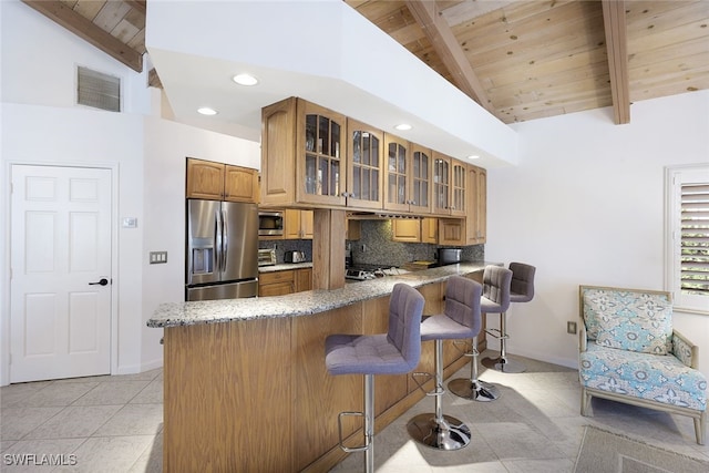 kitchen featuring visible vents, brown cabinets, a peninsula, appliances with stainless steel finishes, and tasteful backsplash