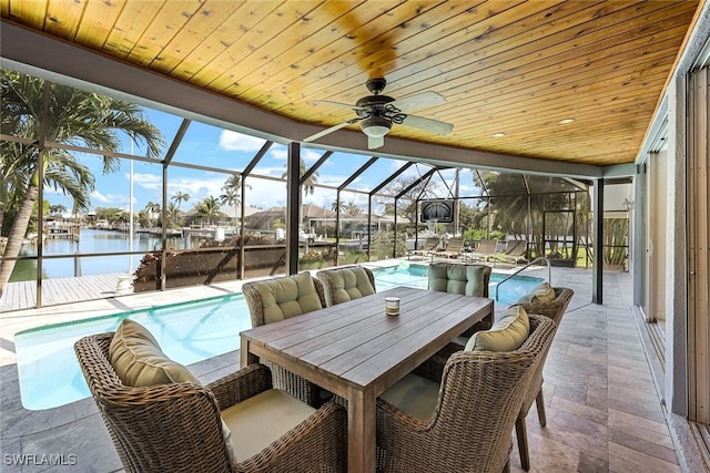 outdoor pool with a water view, glass enclosure, outdoor dining area, a patio area, and a ceiling fan