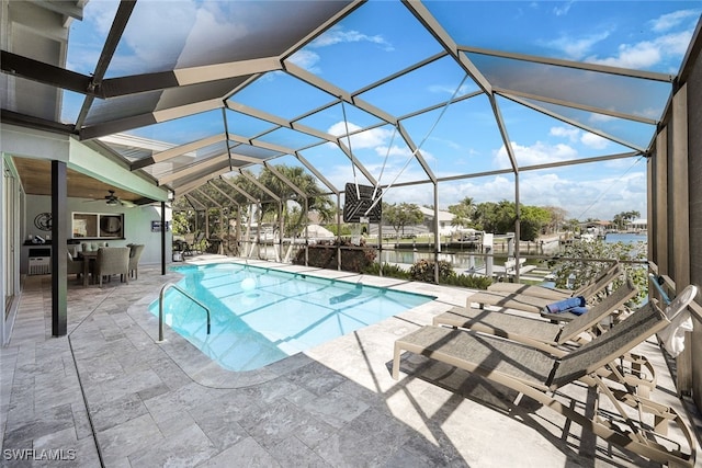 outdoor pool with ceiling fan, a water view, glass enclosure, a patio area, and a boat dock