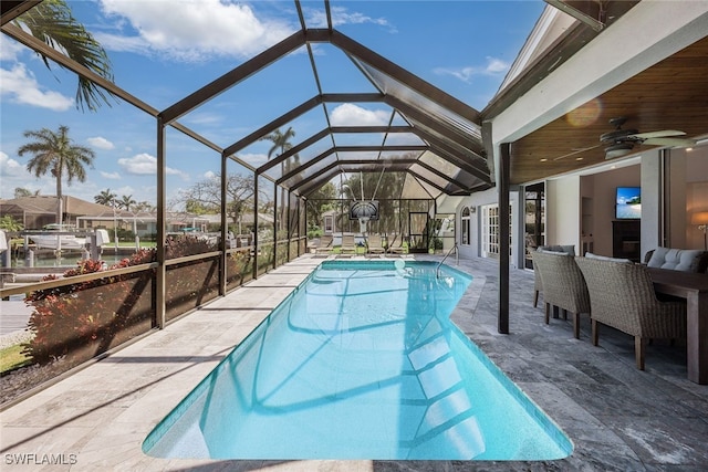 pool featuring glass enclosure, an outdoor hangout area, ceiling fan, and a patio area