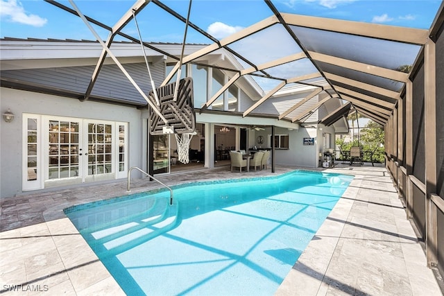 outdoor pool with a lanai, a patio area, and french doors