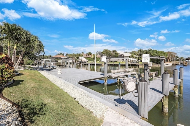 dock area with a water view, boat lift, and a lawn