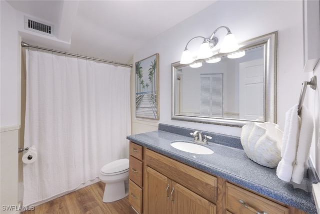 full bathroom with vanity, a shower with shower curtain, wood finished floors, visible vents, and toilet