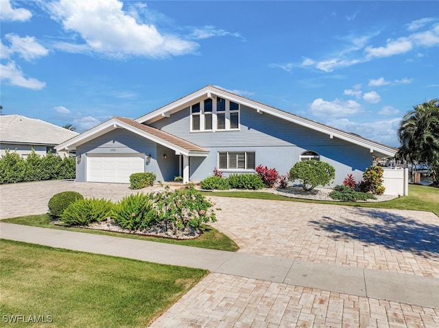 view of front of home with fence, a garage, driveway, and stucco siding