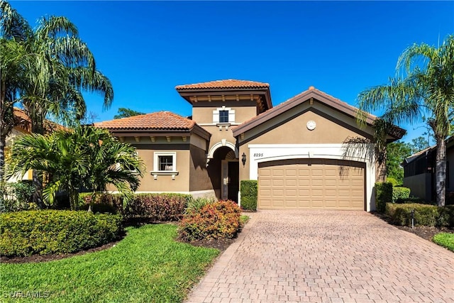 mediterranean / spanish home featuring decorative driveway, a garage, stucco siding, and a tile roof