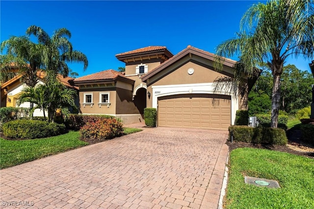 mediterranean / spanish-style house with a tile roof, decorative driveway, a garage, and stucco siding