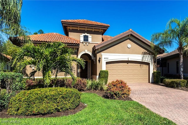 mediterranean / spanish house featuring stucco siding, a garage, driveway, and a tiled roof