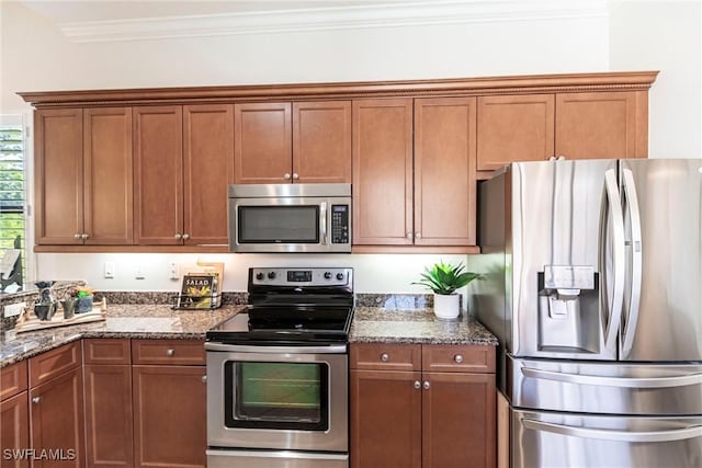 8295 Provencia Ct, Fort Myers, FL 33912 - kitchen with stainless steel appliances, brown cabinets, dark stone countertops, and ornamental molding