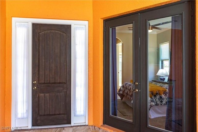 entryway with crown molding and french doors