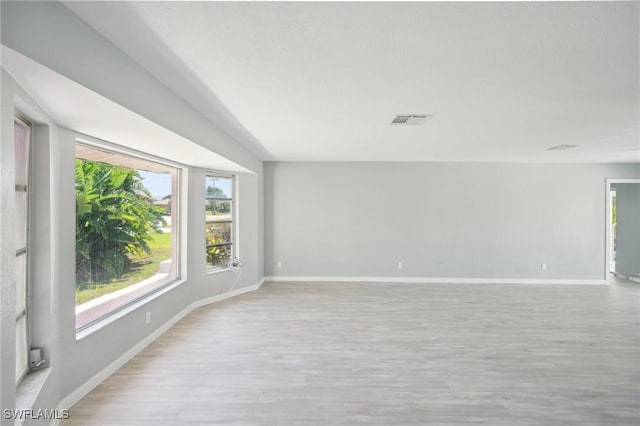 spare room with baseboards, visible vents, and light wood finished floors