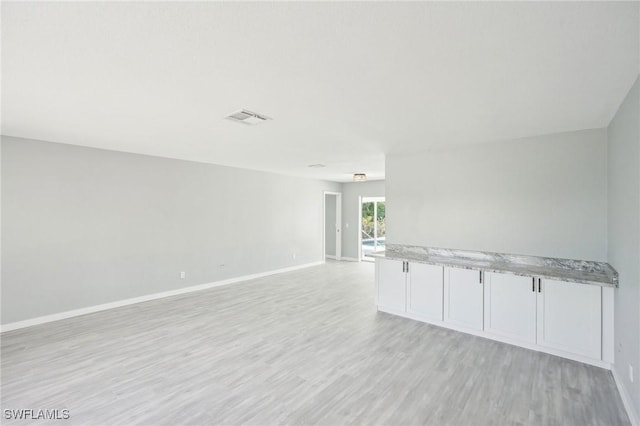 spare room with light wood-style flooring, baseboards, and visible vents