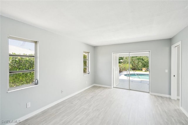 spare room with baseboards and light wood-style floors