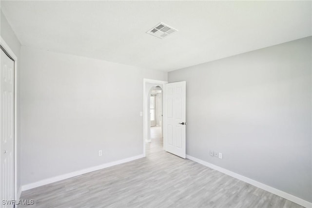 unfurnished bedroom featuring visible vents, baseboards, a closet, and wood finished floors