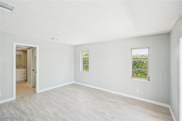 unfurnished bedroom featuring multiple windows, light wood-style floors, visible vents, and baseboards