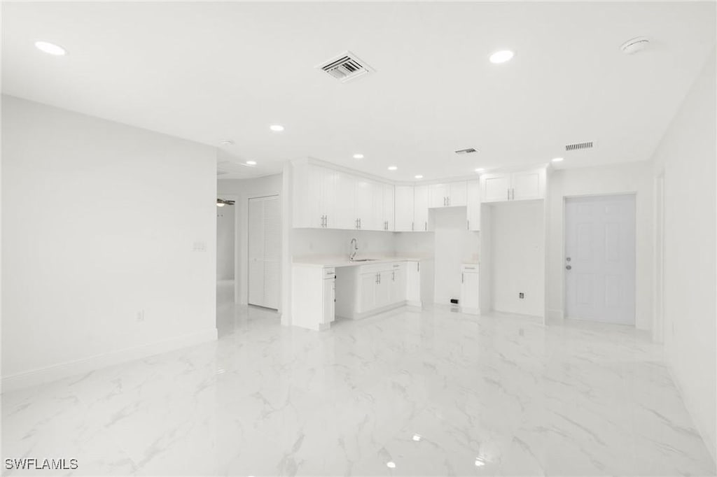 unfurnished living room featuring recessed lighting, visible vents, and baseboards