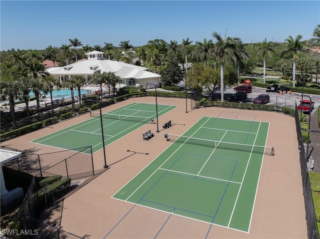 view of tennis court featuring community basketball court and fence