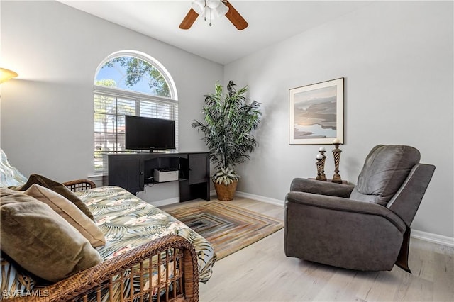 living room featuring baseboards, light wood-style floors, and a ceiling fan