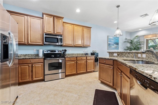 kitchen featuring visible vents, pendant lighting, stone counters, appliances with stainless steel finishes, and a sink