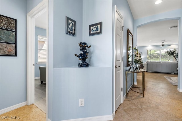 hall featuring visible vents, arched walkways, baseboards, and light tile patterned flooring