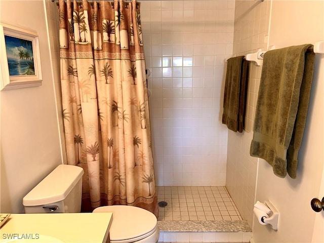 bathroom featuring a tile shower, toilet, and vanity