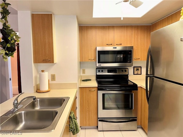 kitchen featuring light countertops, light tile patterned floors, stainless steel appliances, a ceiling fan, and a sink