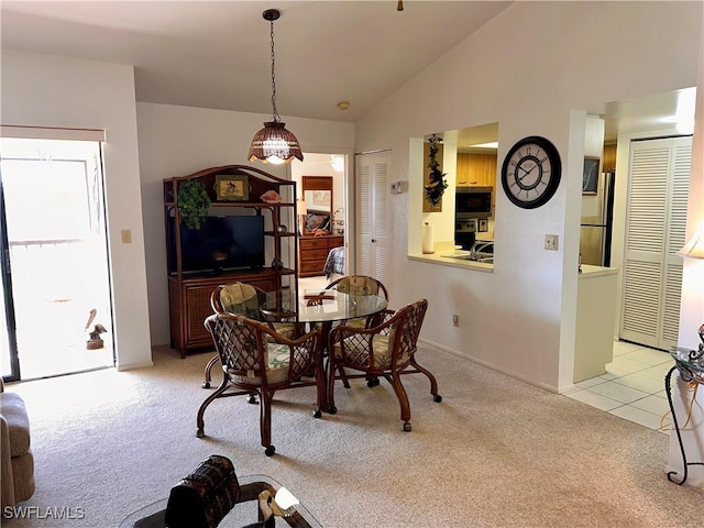 dining space with light colored carpet and high vaulted ceiling