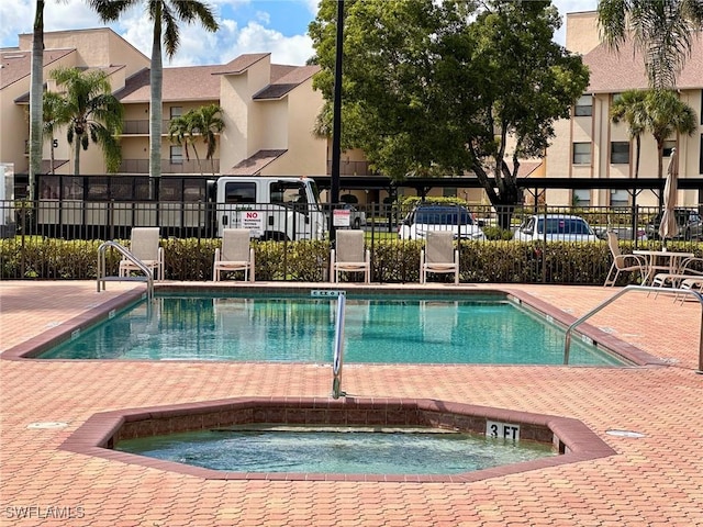 view of swimming pool with a community hot tub and fence