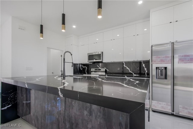 kitchen with dark stone counters, a sink, appliances with stainless steel finishes, modern cabinets, and backsplash